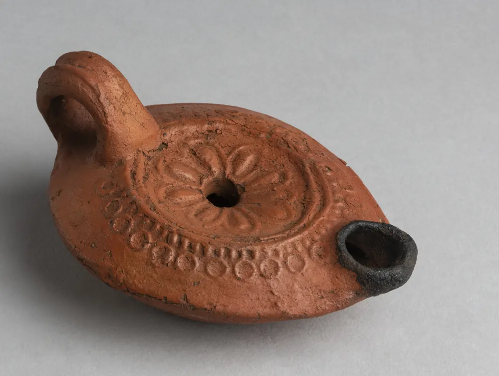 A Roman clay oil lamp with a rosette on its top, made in Roman Egypt between 30 BC and AD 395